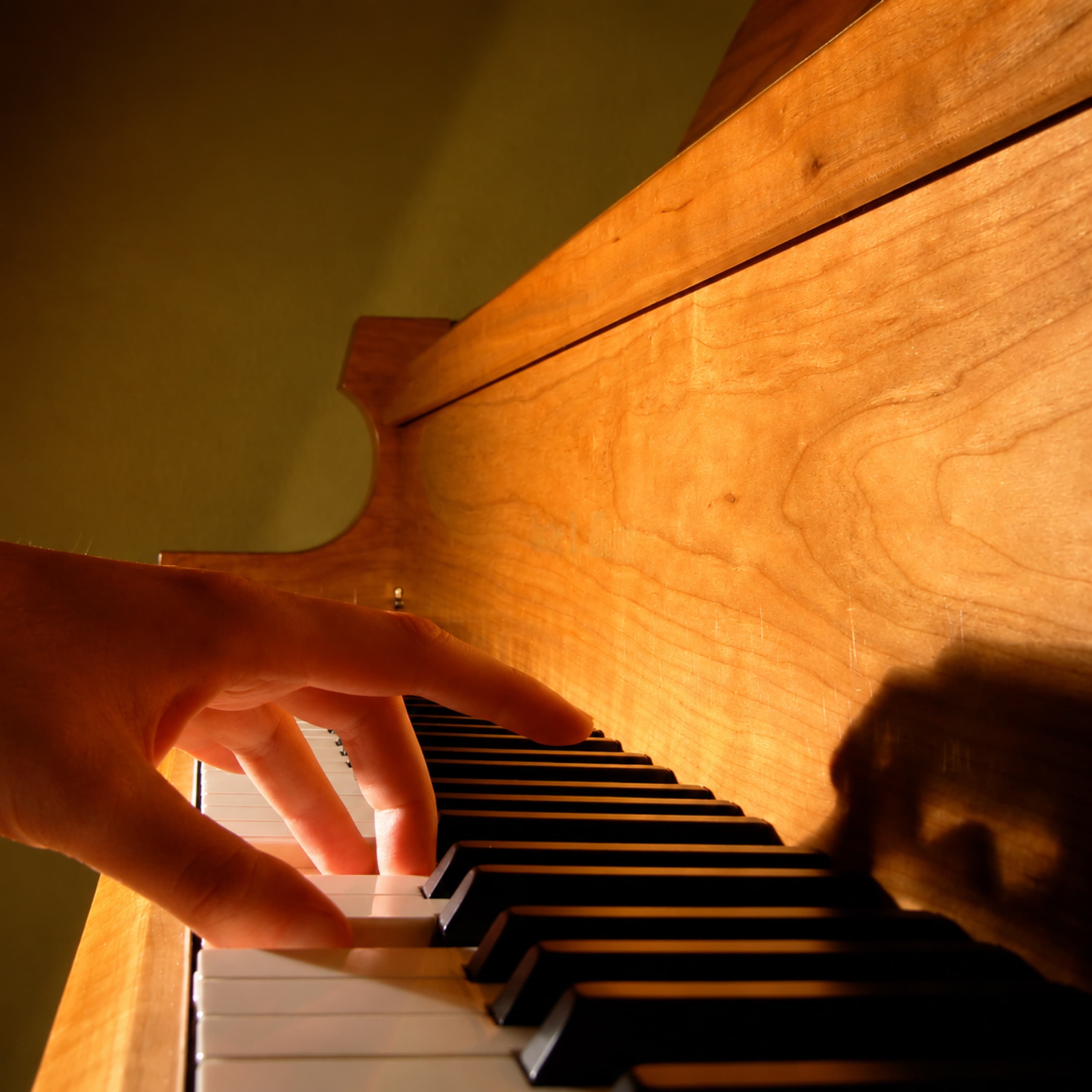 A hand improvising at an upright piano